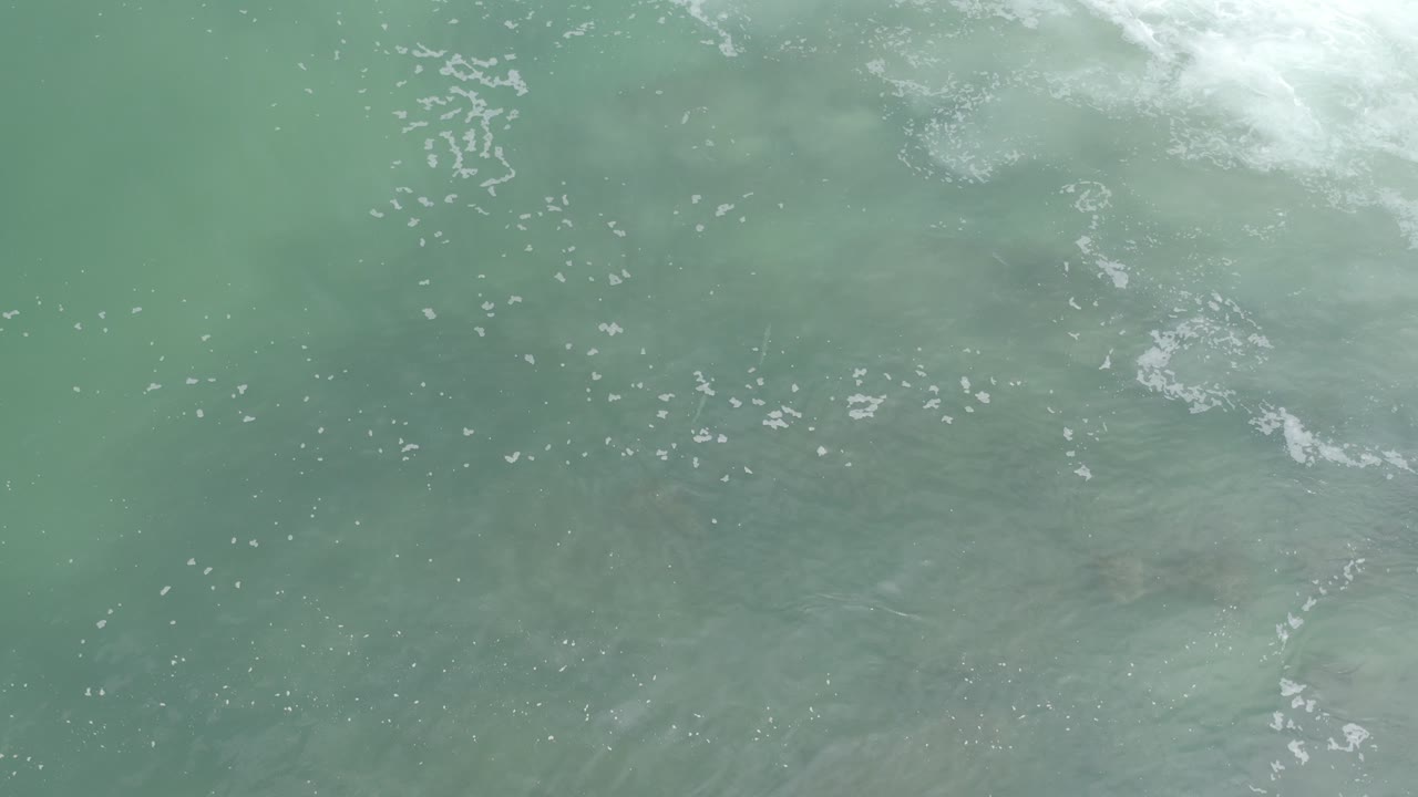 Turquoise-green seawater with white foam near the top edge.