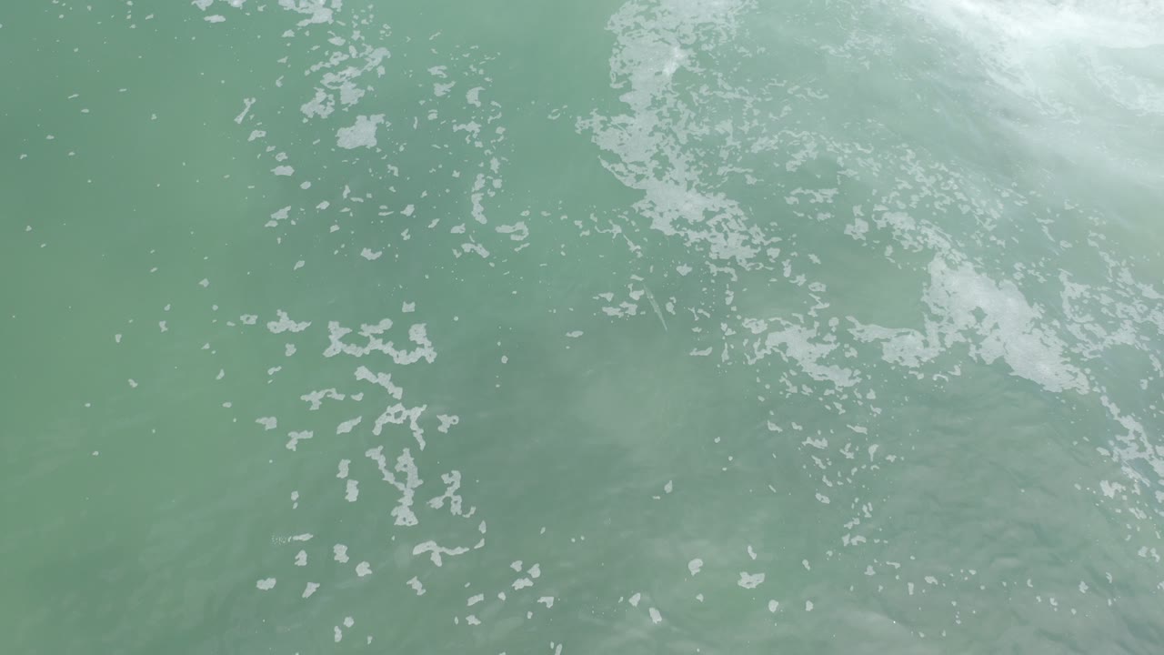 Pale green-gray water with white foam from above