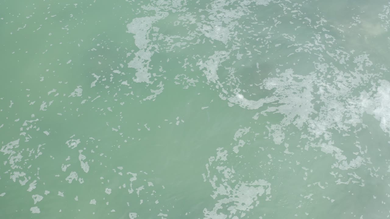 Foamy ocean surface over pale green water