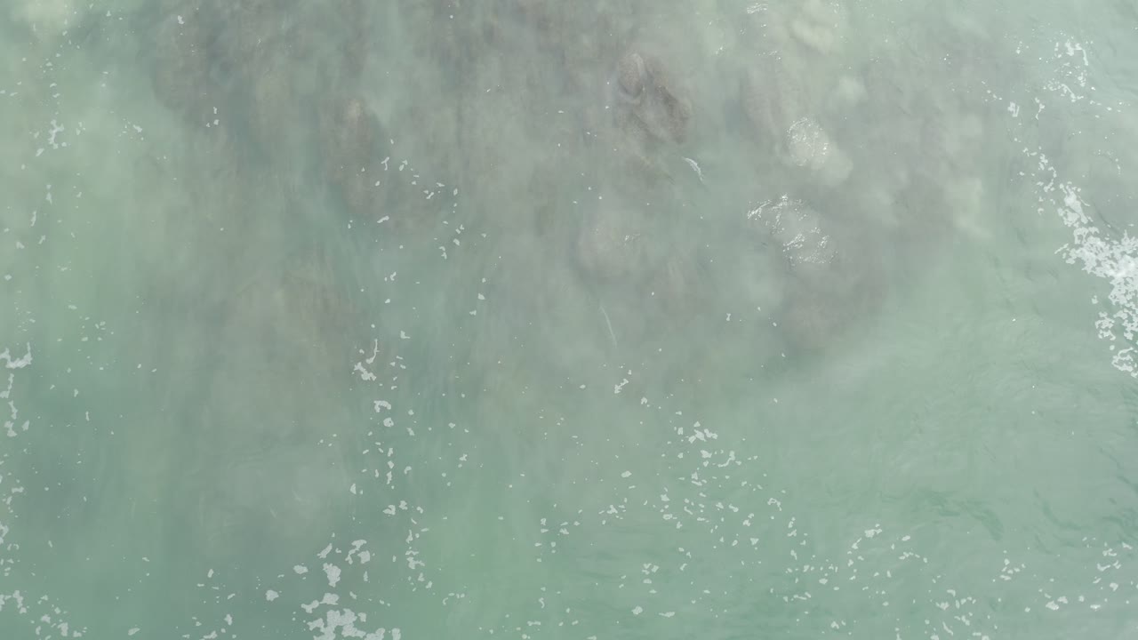 Foamy ocean water with darker sand patterns below
