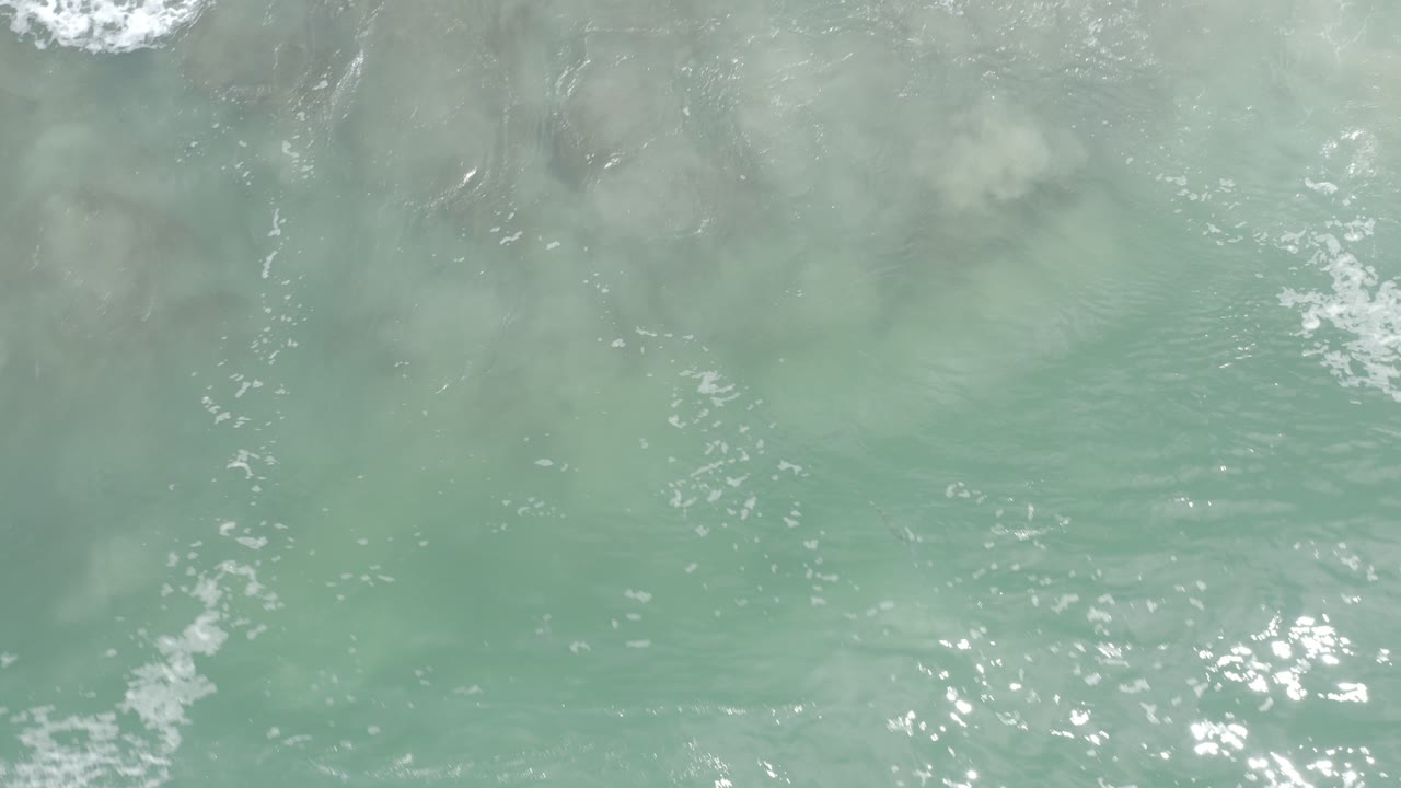Overhead turquoise ocean water with small foam patches
