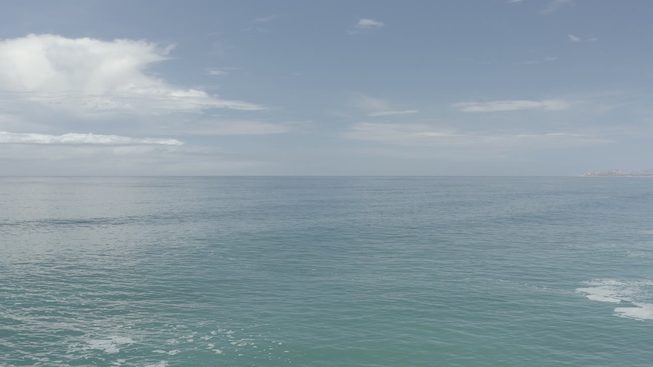 Blue-green ocean under a pale sky with small foam lines
