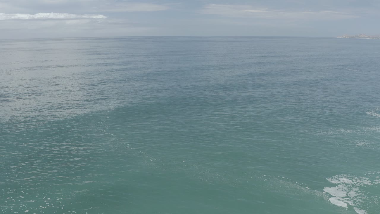 Calm sea surface below a hazy sky with distant coastline.