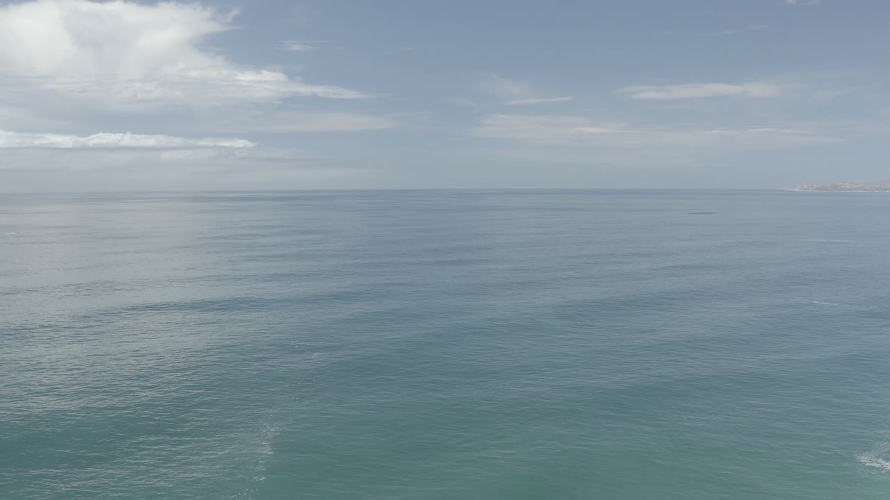 Blue-green sea below a wide sky with scattered clouds.