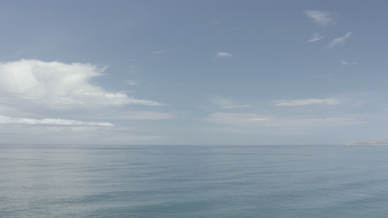 Opening frame of Los Cabos ocean water under a partly cloudy blue sky, with a level horizon and no visible people.