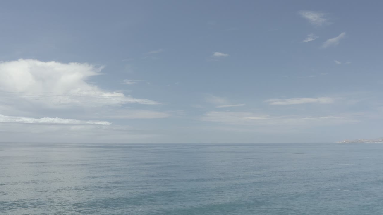 Blue-green water and broad sky with far land at right