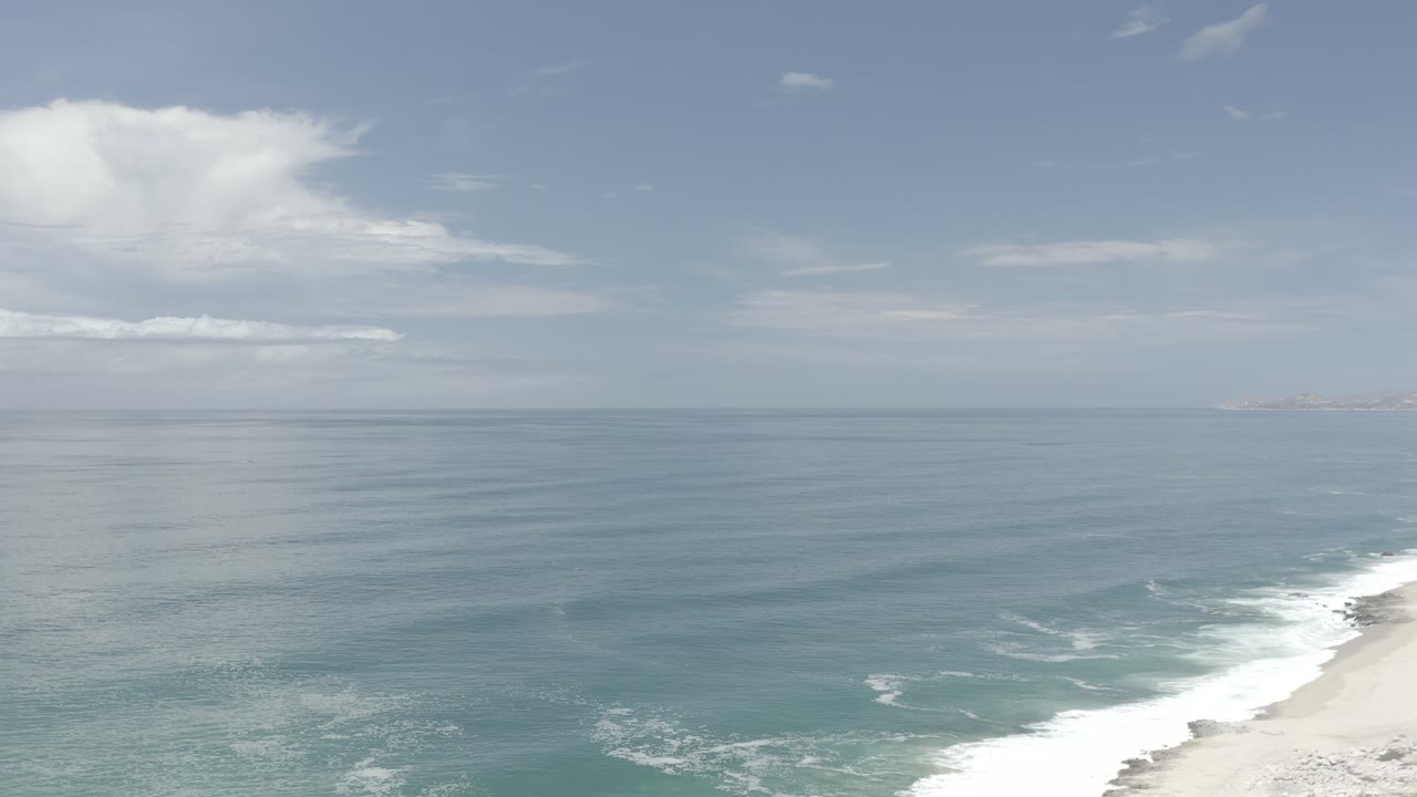 Calm ocean surface with waves breaking near the beach.