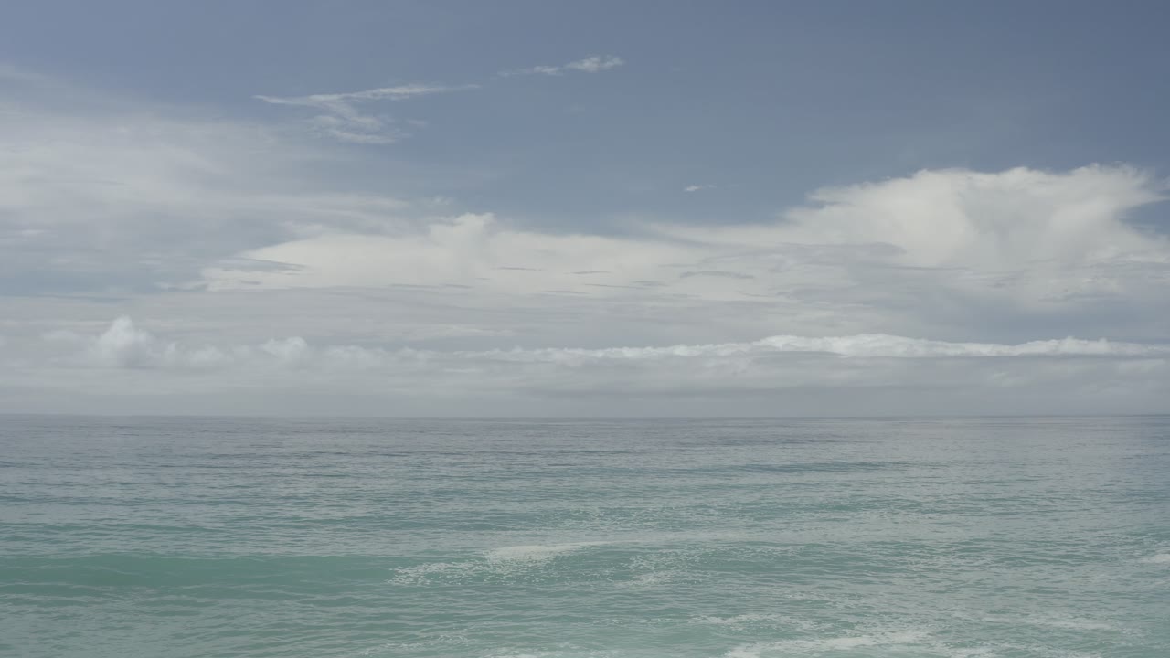 Open sea beneath a pale sky with white clouds