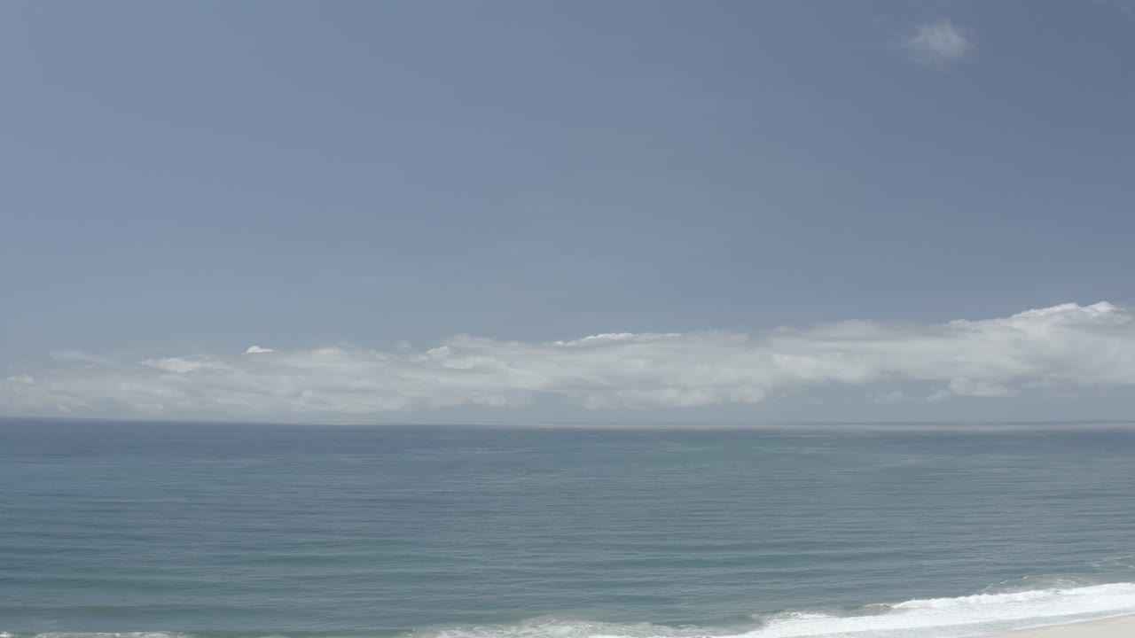 At 0:01, the Los Cabos horizon remains centered while a brighter line of surf reaches farther across the lower edge, with no visible people.
