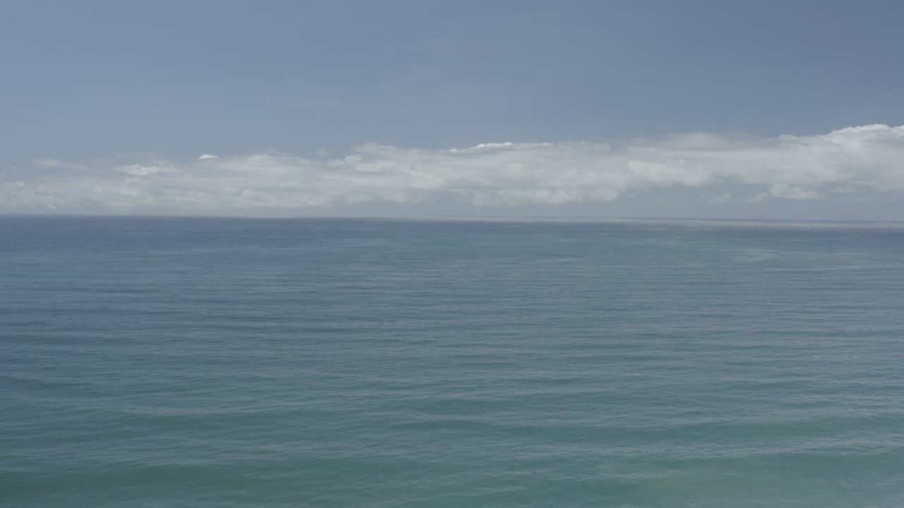 Blue-green Los Cabos ocean fills the foreground and midground, with soft wave bands leading toward a straight horizon and no visible people.