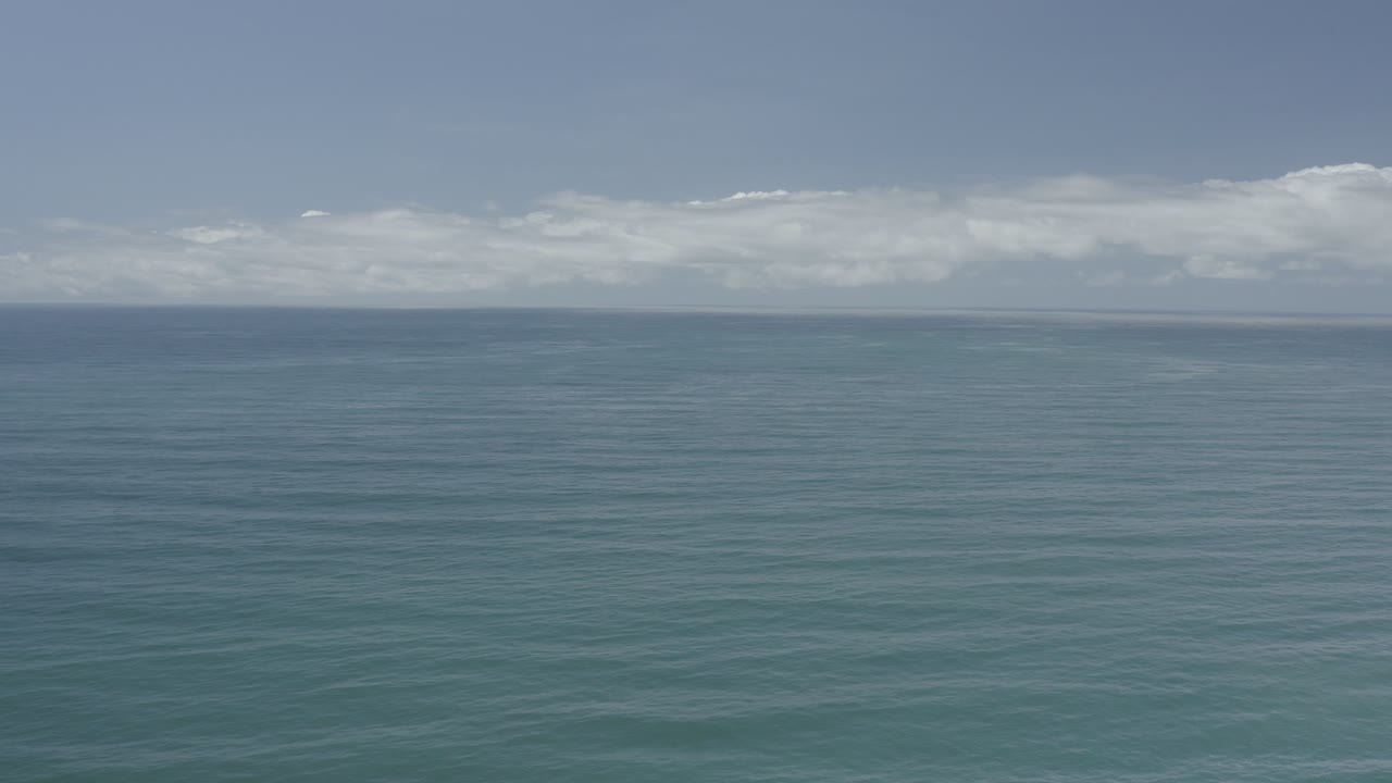 Calm sea surface below pale clouds