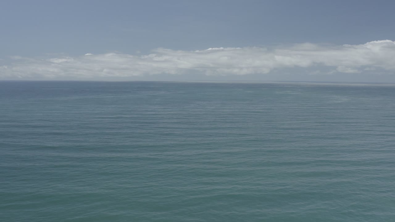 Opening frame of the Los Cabos, Mexico ocean with blue-green water, a distant horizon, low white cloud bands, and no visible people.