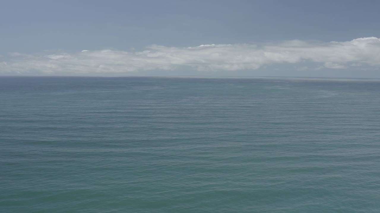 Wide ocean surface beneath scattered white clouds
