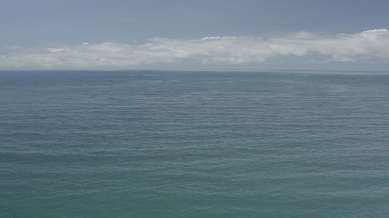 Los Cabos ocean surface fills the frame with soft ripples, a thin distant horizon, layered clouds, and no visible people.