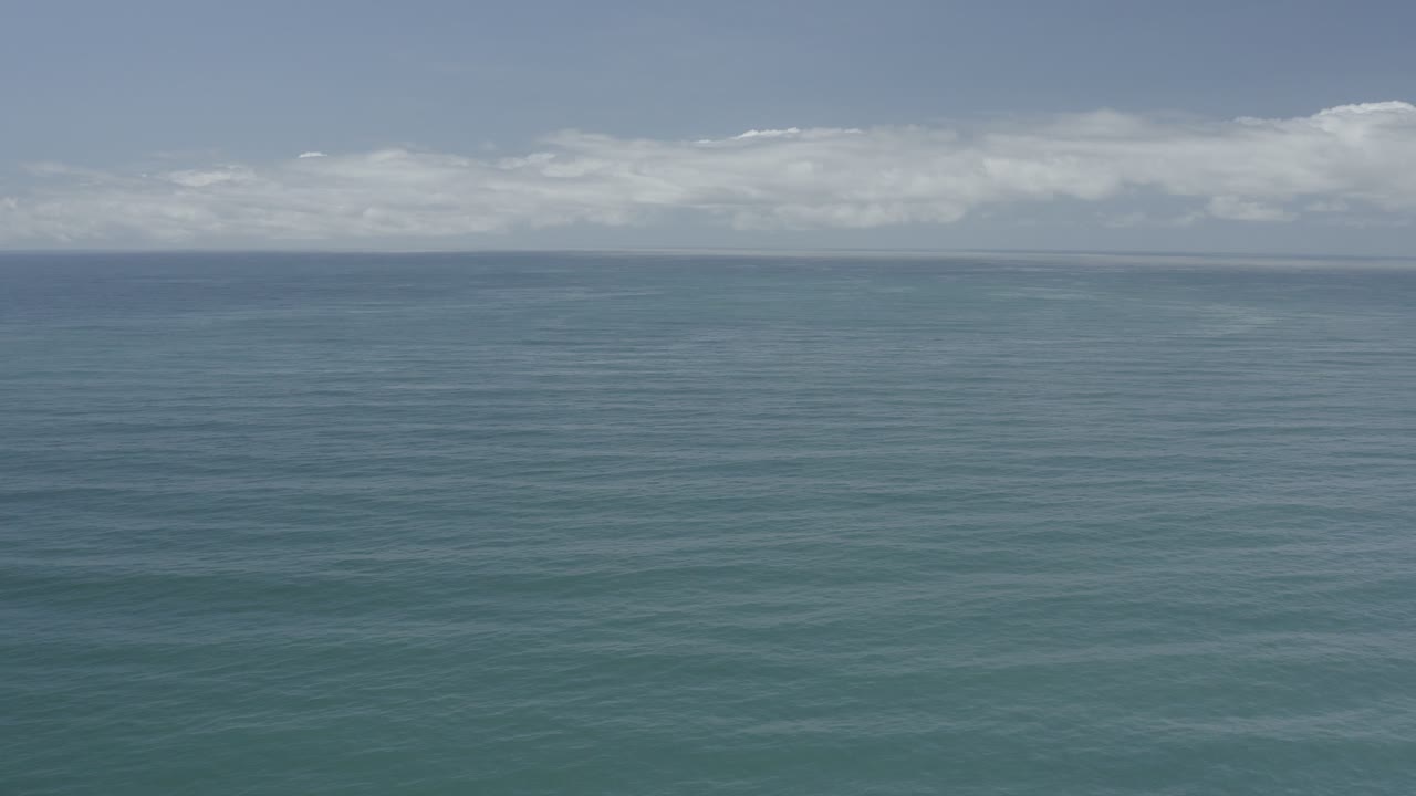 Blue ocean and cloudy sky seen from an elevated angle.