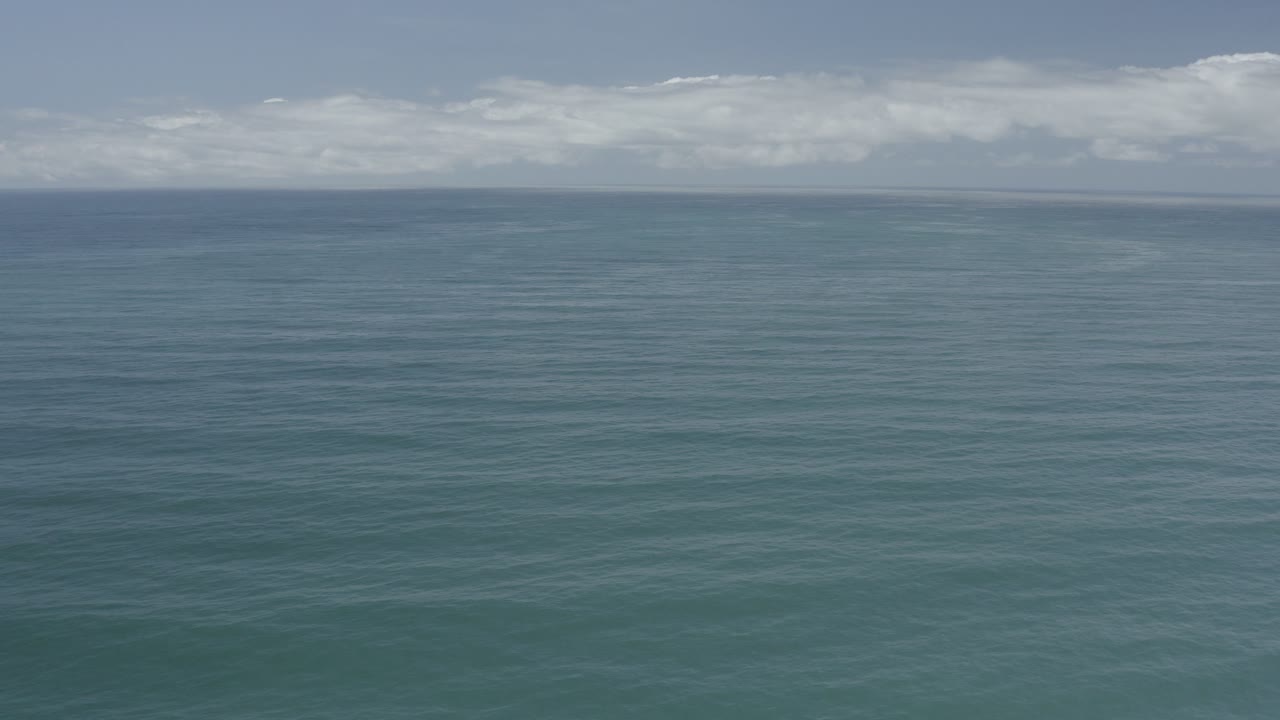 Blue-green water below a cloudy coastal sky