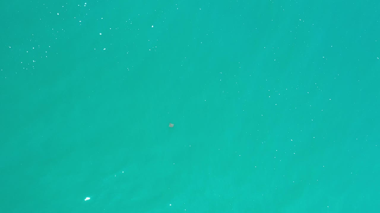 Open turquoise water with faint shadowy patches below.