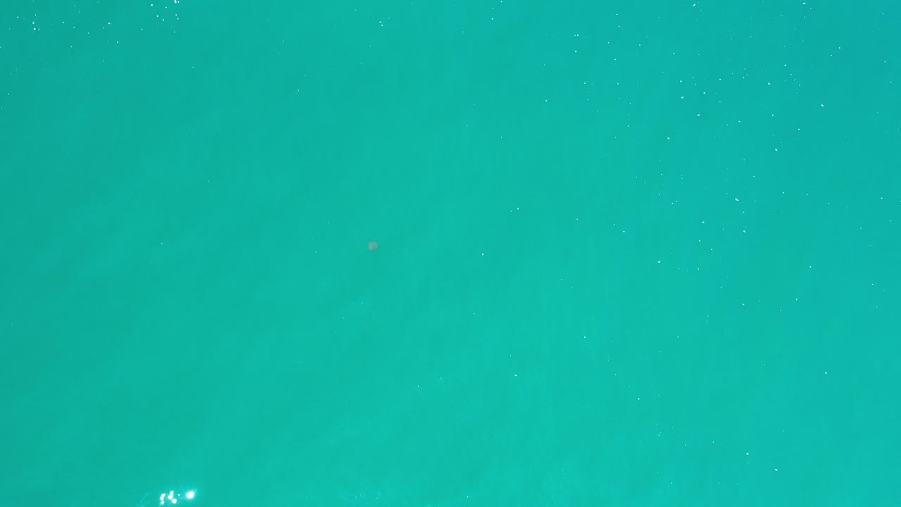 Blue-green ocean water fills the first Los Cabos frame with a few small sun reflections and no visible people.