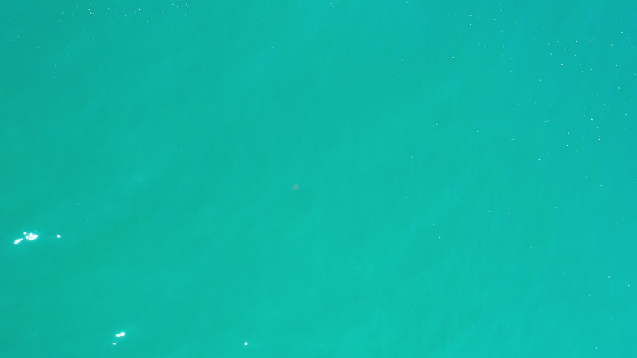Top-down turquoise ocean water with small white light glints.