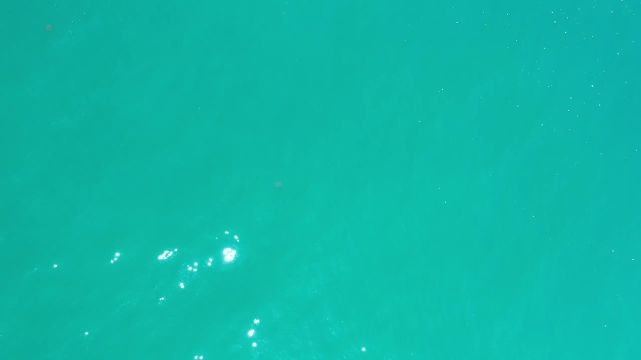 Overhead clear aqua water in Los Cabos, Mexico, with subtle darker areas under the surface and no visible people.