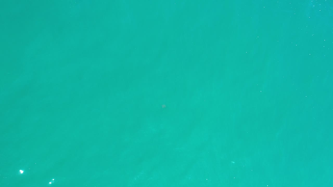 Turquoise water fills the frame in Los Cabos, Mexico, with a few small white surface glints and no visible people.