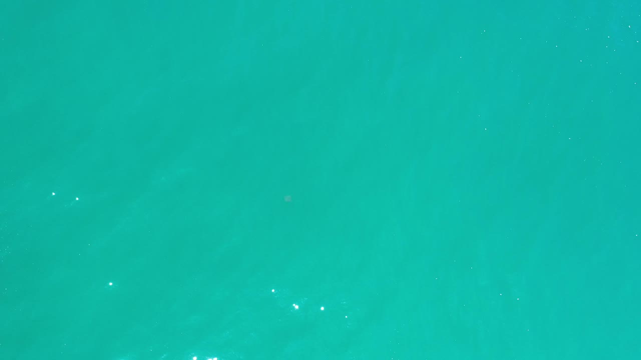 Smooth turquoise water with faint darker patches below the surface.