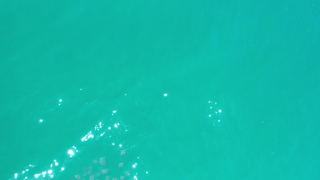Turquoise water with bright wave glints near the lower left.