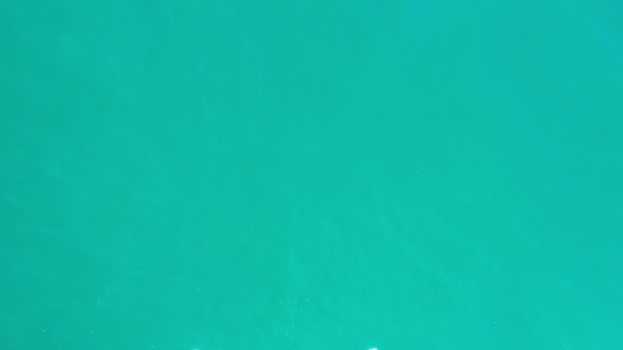 Teal ocean water in Los Cabos fills the frame with faint darker current bands under the surface and no visible people.