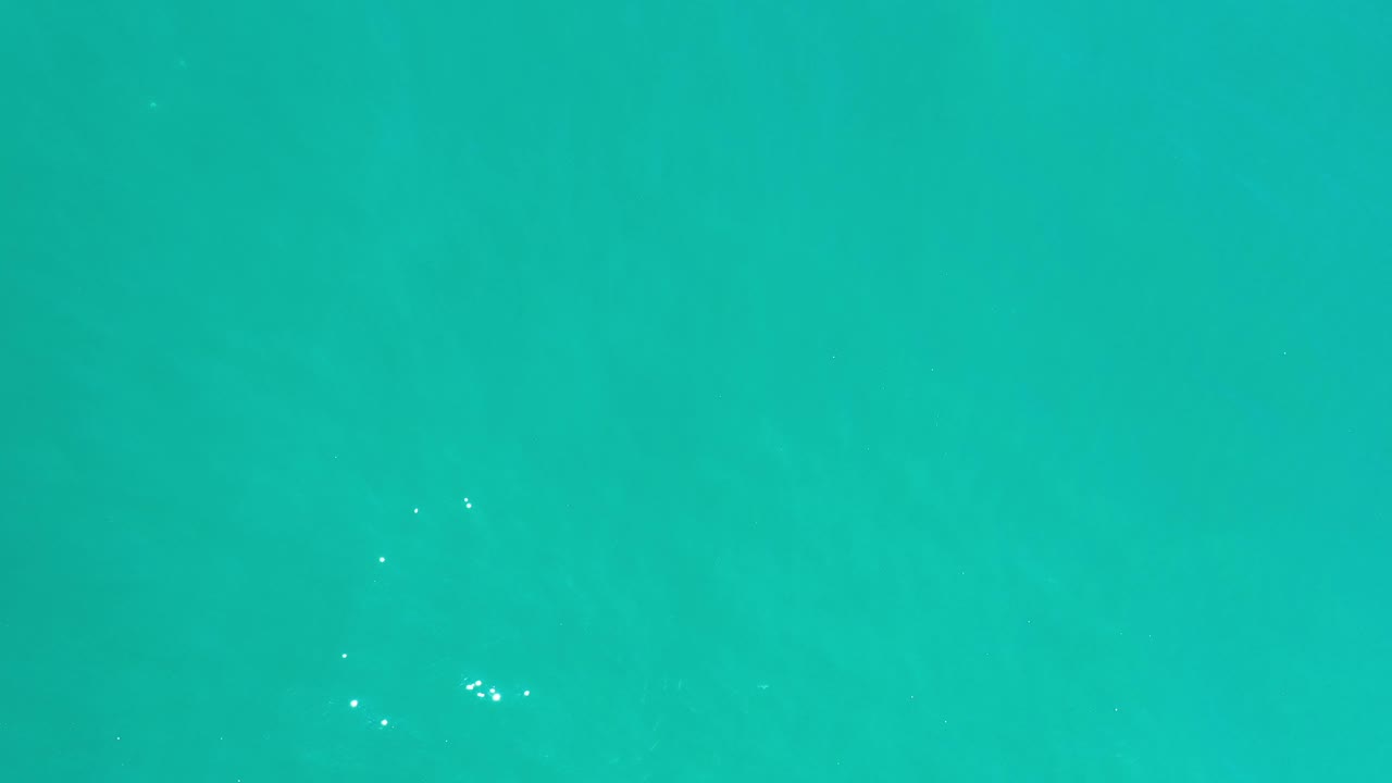 Teal water with a horizontal tonal band and scattered white highlights.
