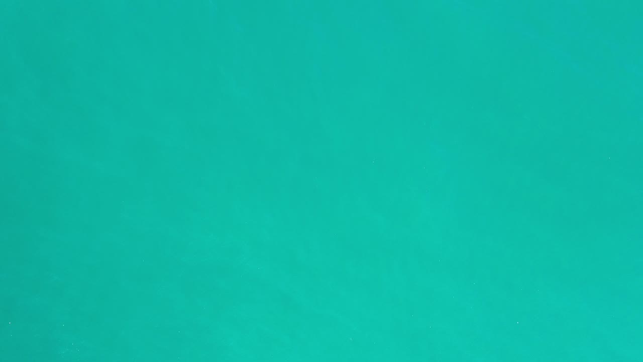 Turquoise water fills the first frame from Los Cabos, Mexico, with faint ripples, subtle horizontal bands, and no visible people.