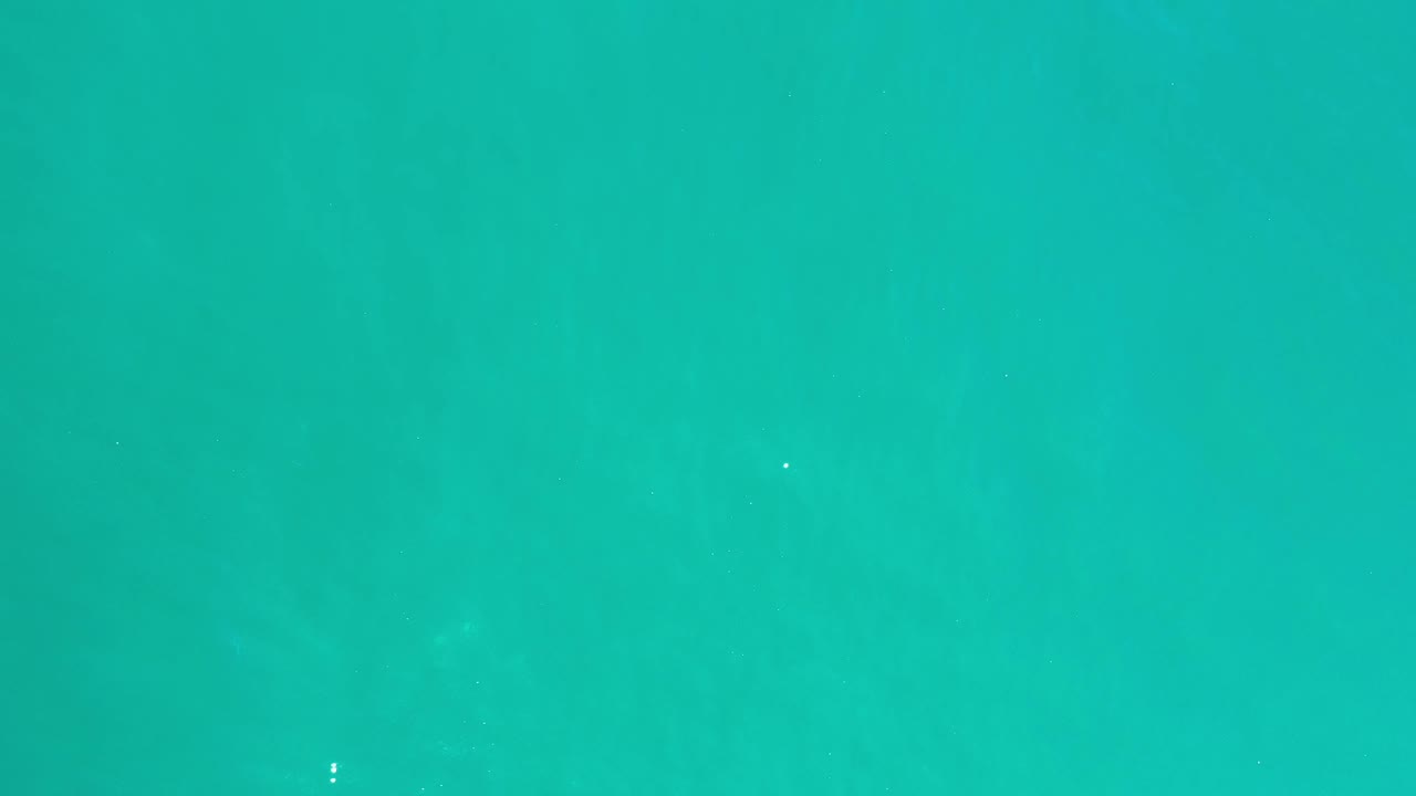 Clear green ocean water in Los Cabos, Mexico, with subtle darker patches under the surface and no visible people.