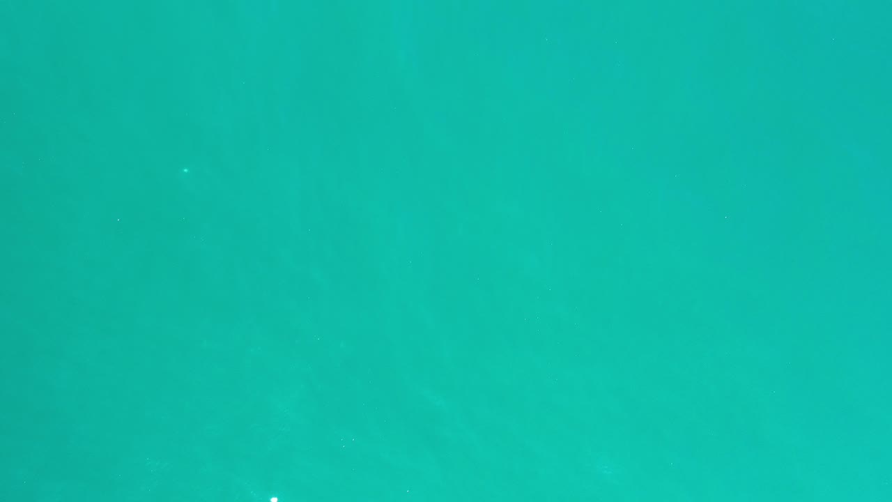 Top-down view of turquoise ocean water in Los Cabos, Mexico, with faint ripples and no visible people.