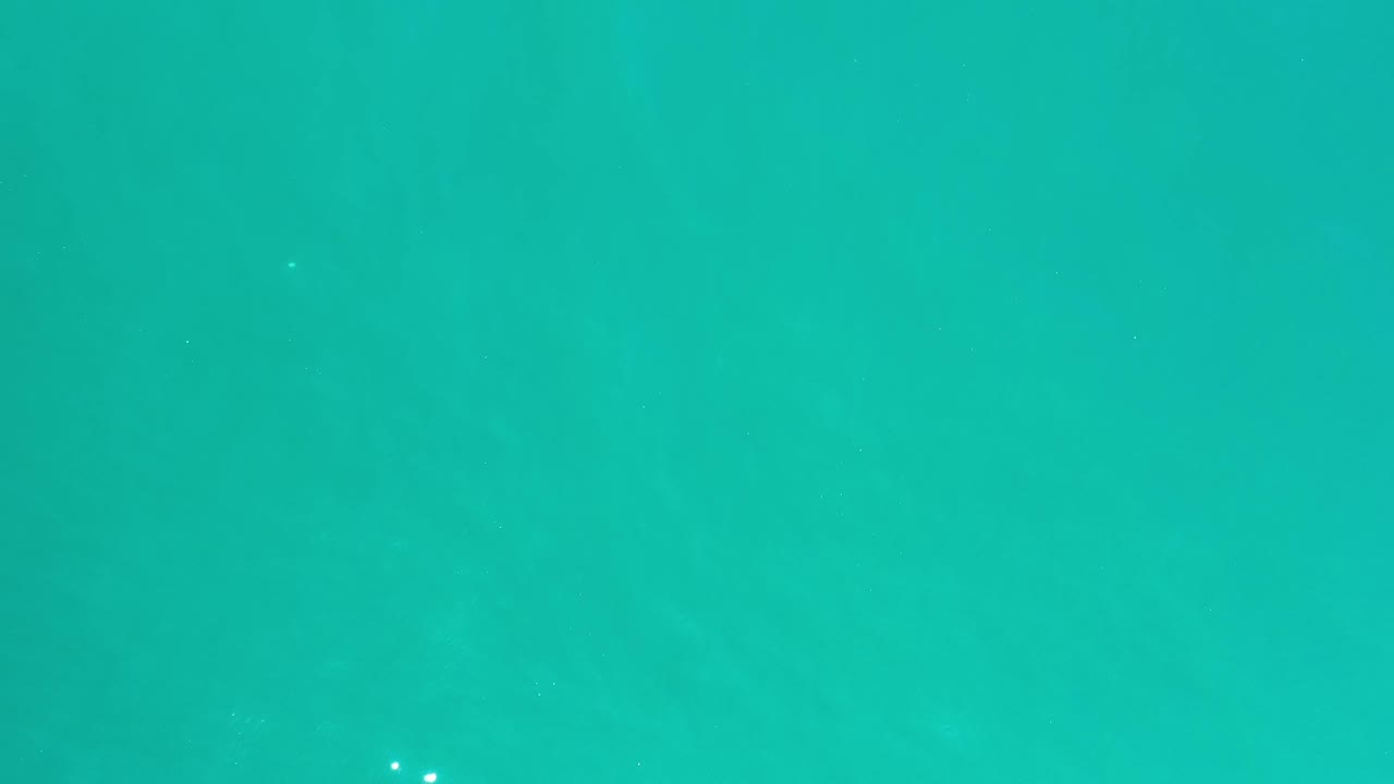 Overhead Los Cabos sea surface with muted blue-green color, soft wave patterning, and no visible people.