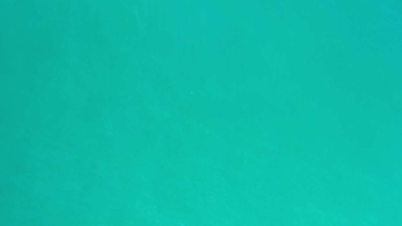 Persian green sea water in Los Cabos fills the frame with soft surface texture and no visible people.