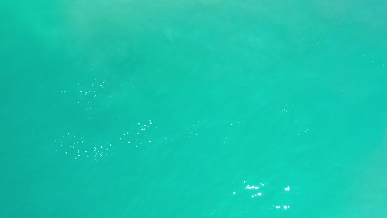Overhead turquoise ocean water in Los Cabos, Mexico, with faint underwater rock or sand shapes near the upper frame and no visible people.