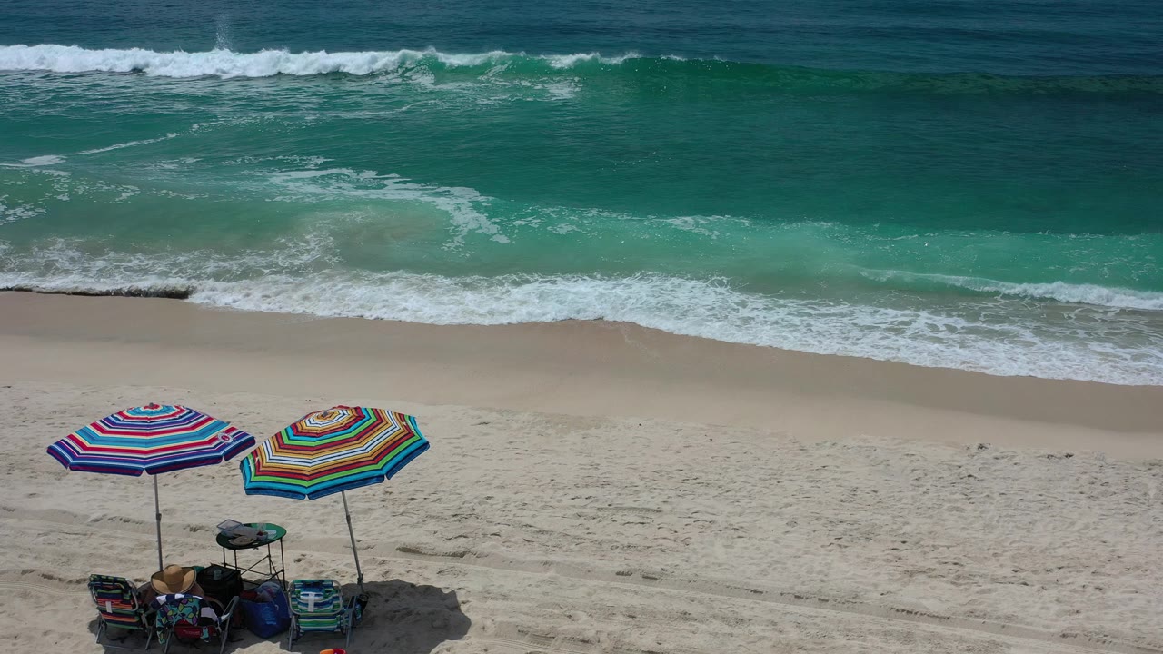 Two colorful umbrellas near the bottom edge with surf behind them.