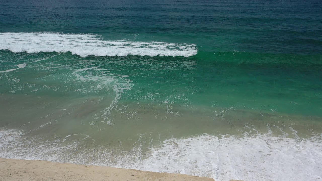 Overhead surf breaking onto a sandy beach