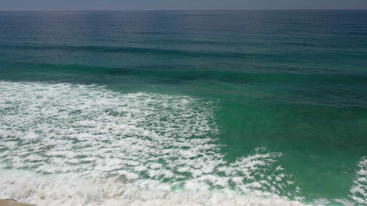 Foamy surf line breaks over clear green water.