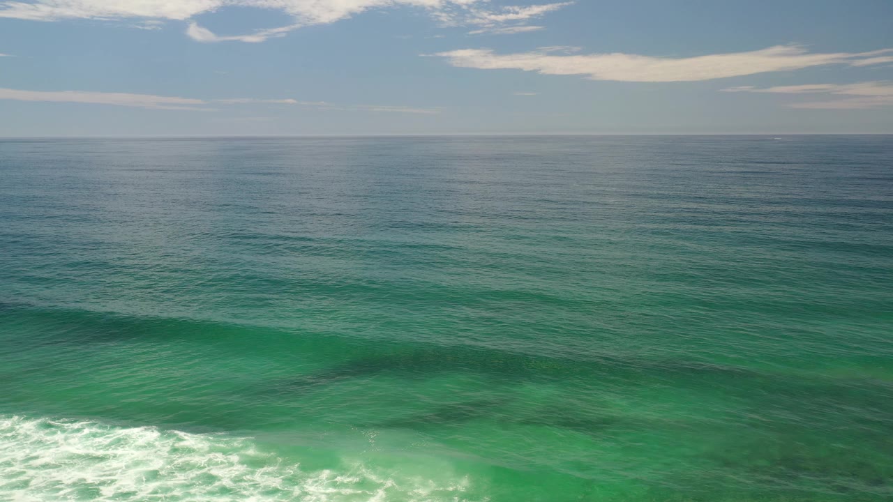 Green surf and distant horizon under scattered clouds.