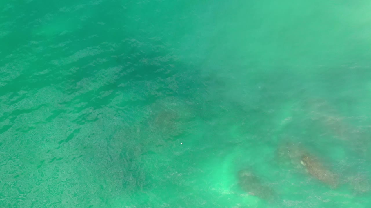Green-blue ocean surface over Los Cabos, Mexico, showing soft wave texture, cloudy underwater forms, and no visible people.