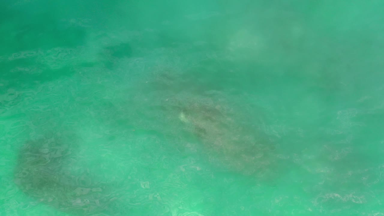 Aerial view of rippled turquoise water over darker underwater patches