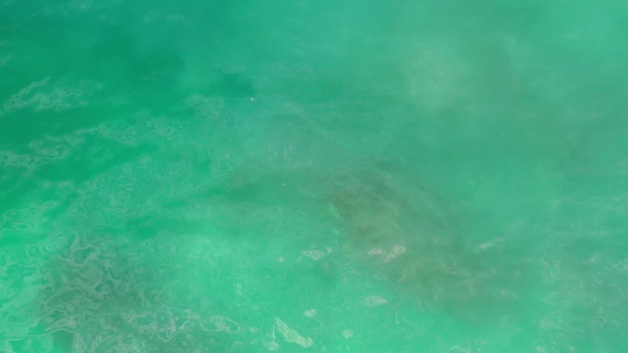 Clear green ocean water with darker bands under the surface.