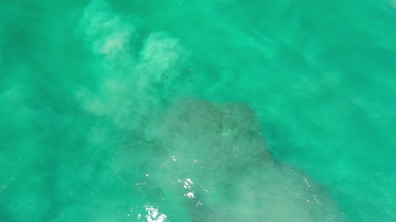 Overhead green ocean water with pale surf over submerged rocks