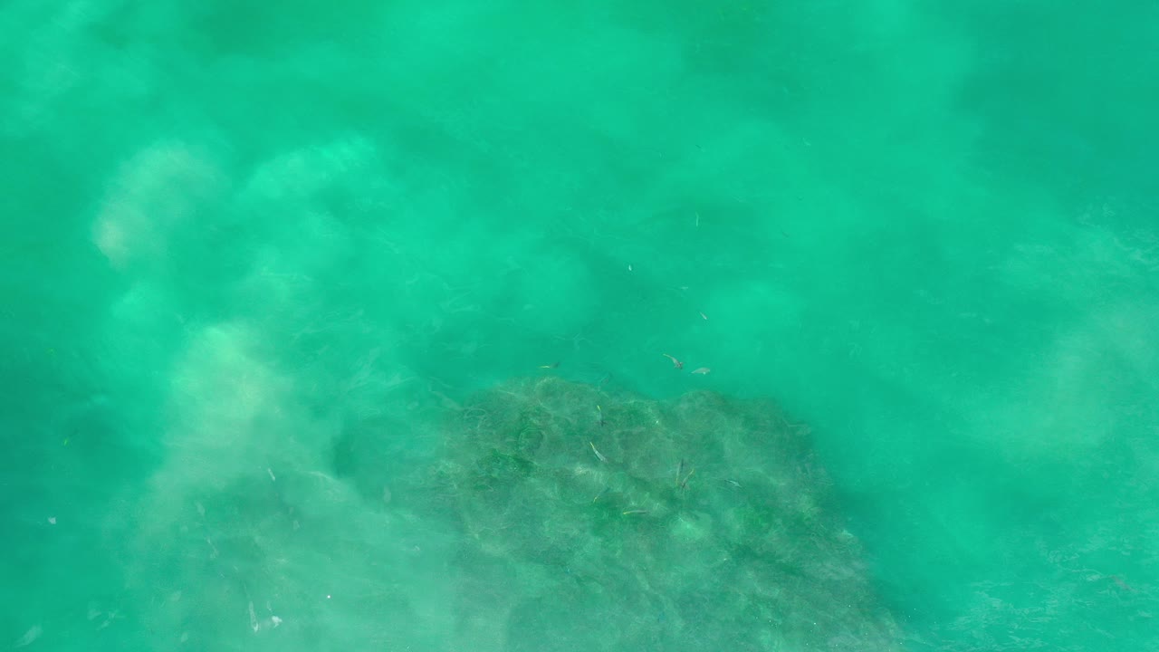 Turquoise water over a dark submerged formation.