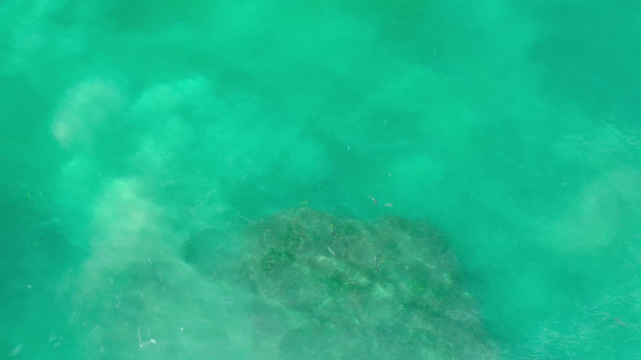 A second overhead view in Los Cabos, Mexico shows cloudy green water passing over a darker underwater formation in the lower frame, with no visible people.