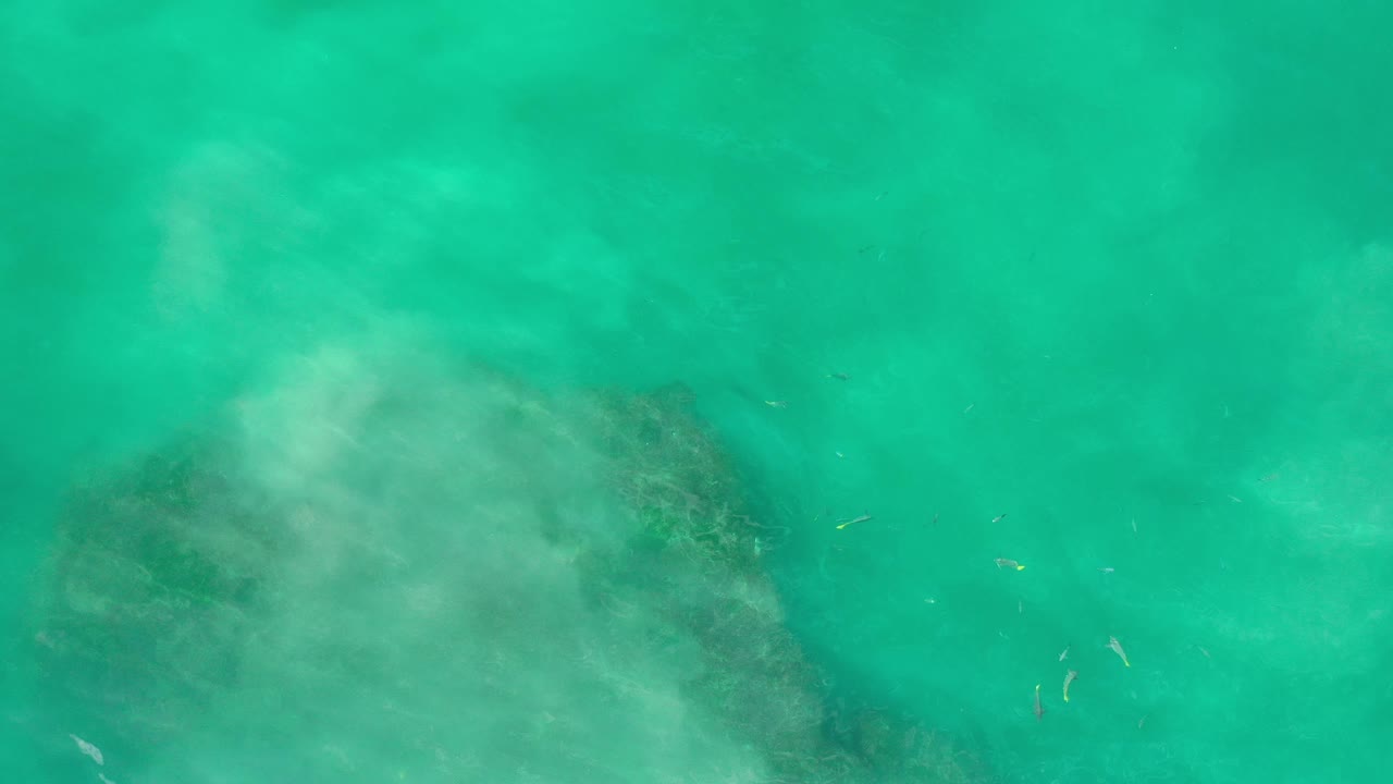 Aerial water surface with pale haze and submerged dark patch