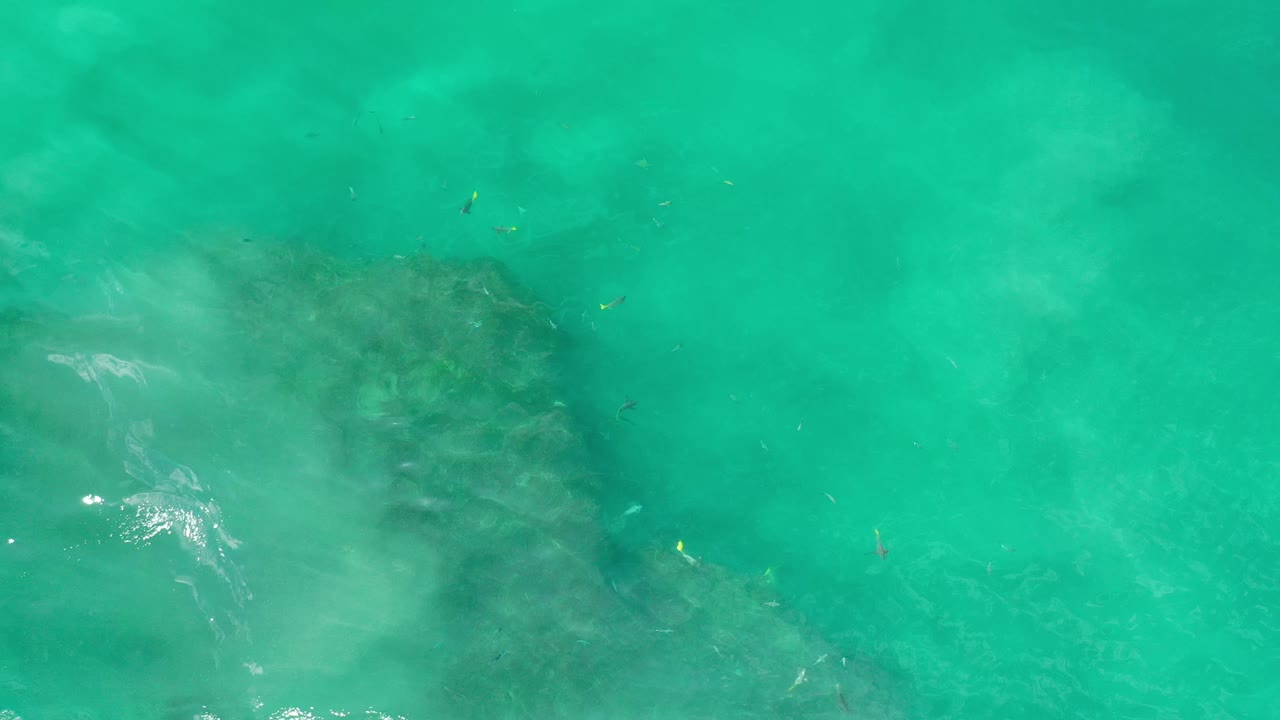 Green ocean surface with underwater rock and pale wash