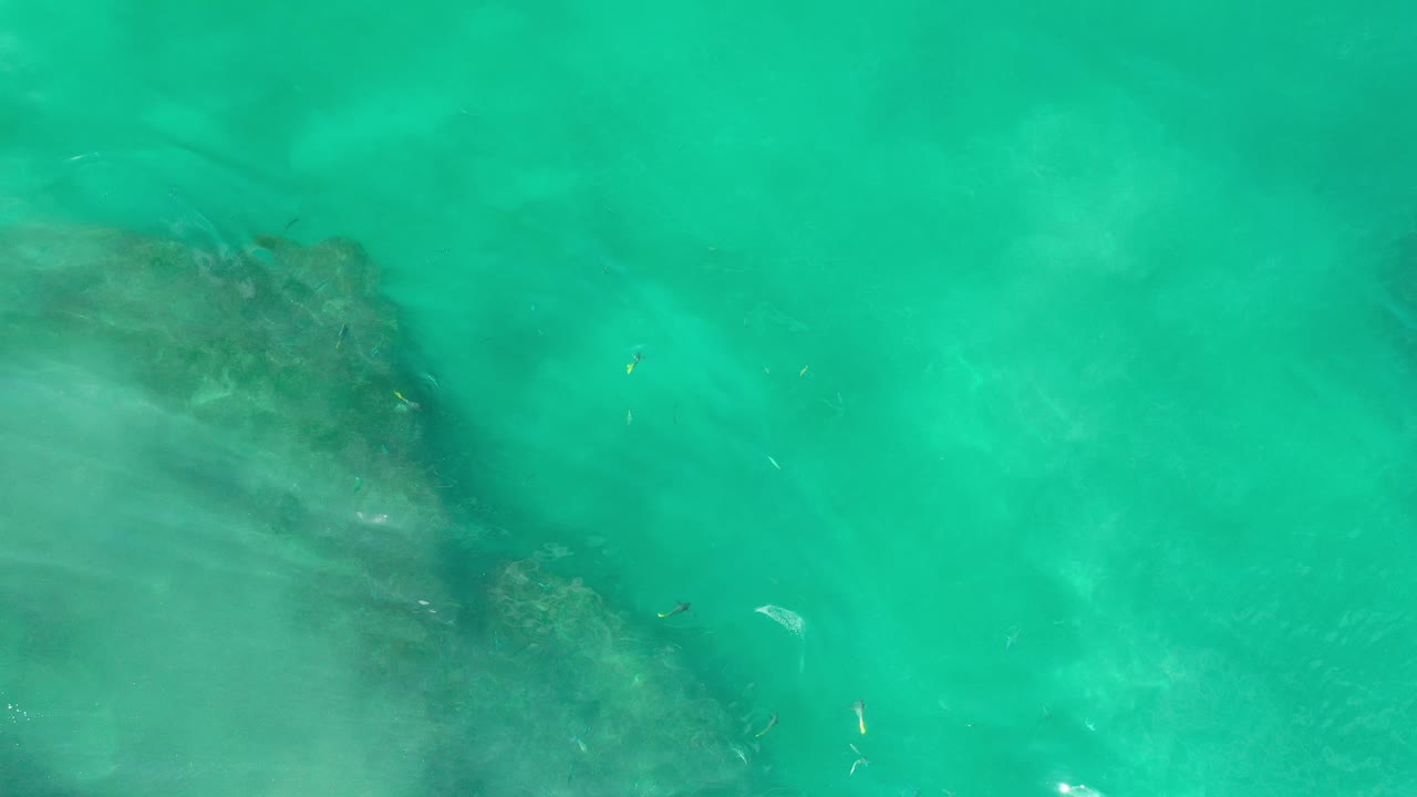 Rock shelf under bright turquoise water.