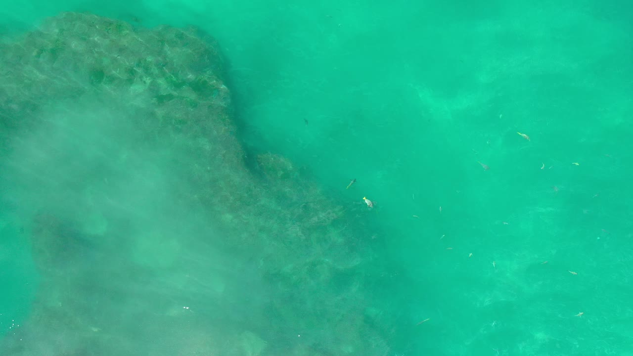 Turquoise water with a dark rock shape beneath the surface.