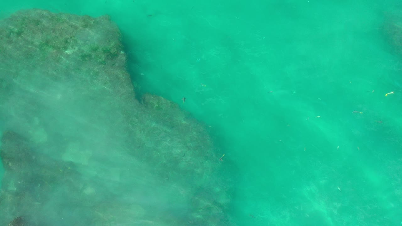 Turquoise water over submerged rocks.